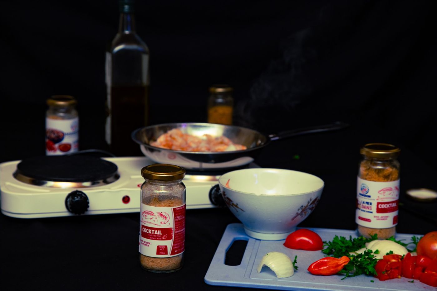 Crevettes qui cuisent à la poêle, pots MARIDOR et légumes coupés sur la planche