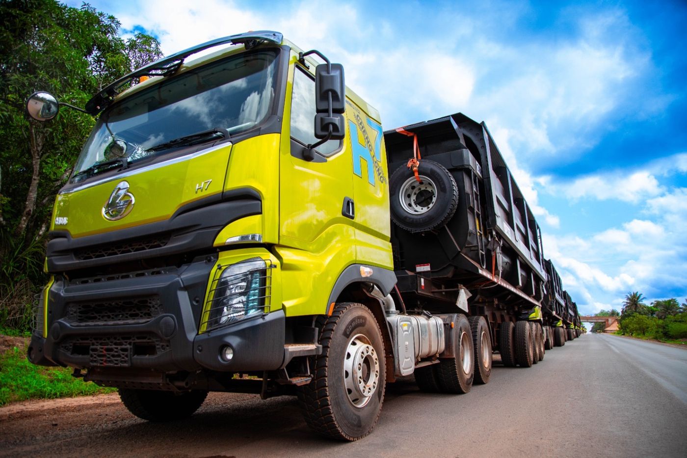Camion-benne vert anis de la flotte SPL vu de près, sous un ciel bleu