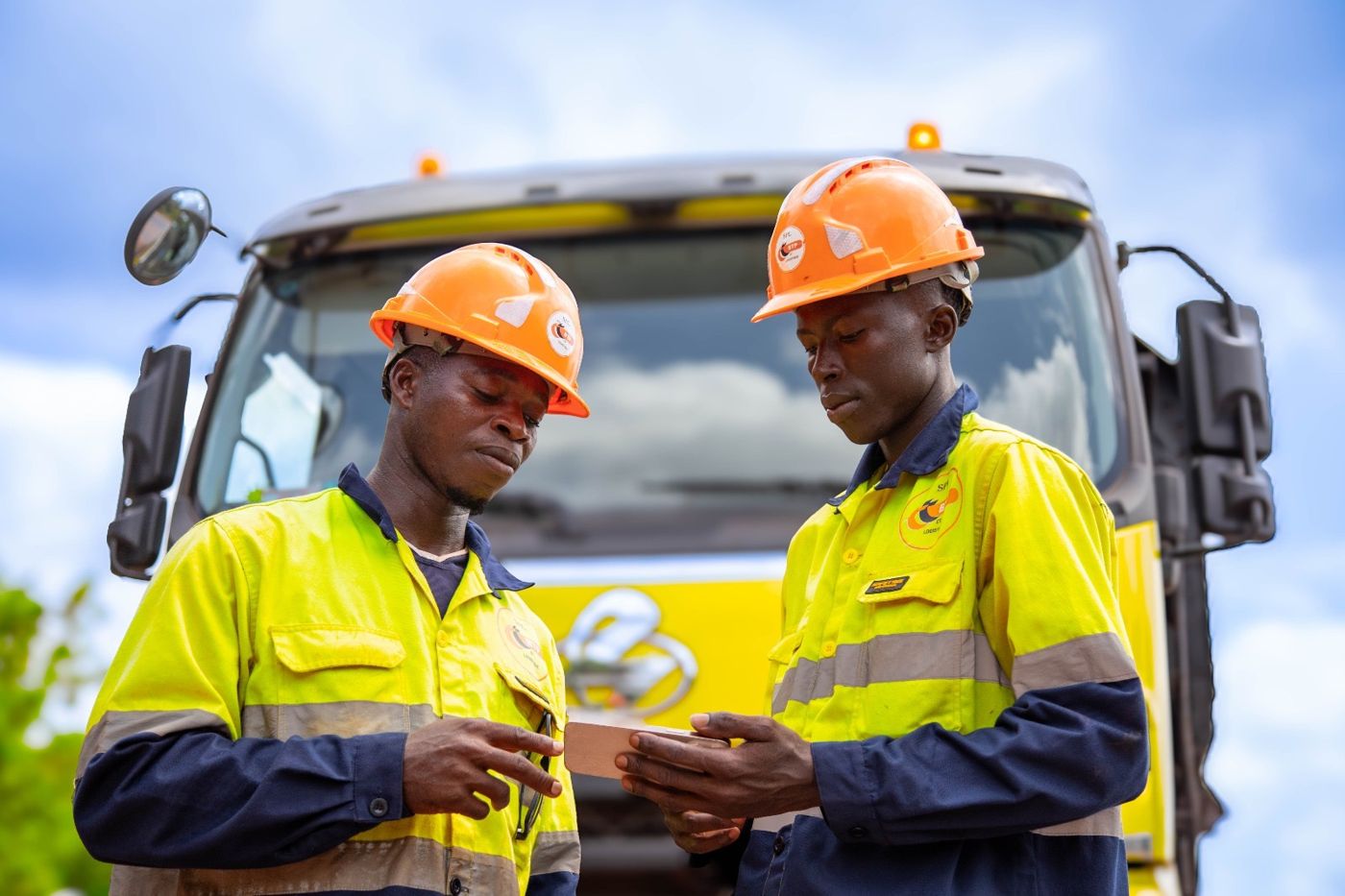Deux employés SPL en casque et tenue haute visibilité devant un camion